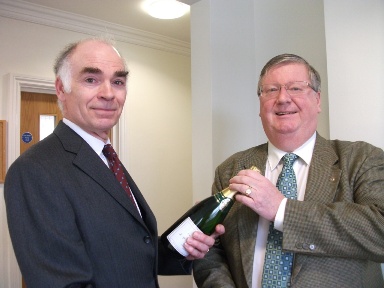 Ian Smith (left) receiving a bottle of champagne from Richard Price of Price Bailey Chartered Accountants